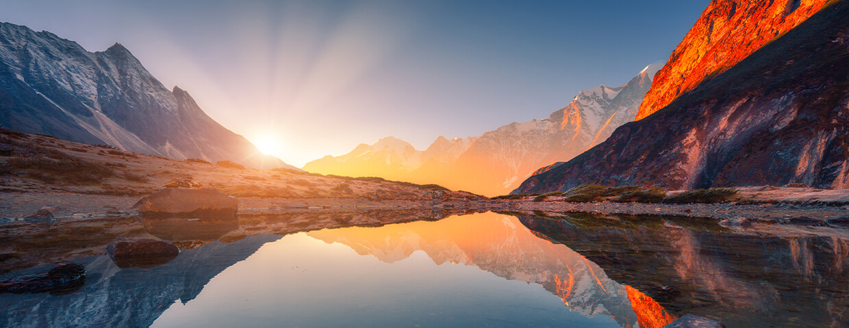 Body of water near mountain in sunset