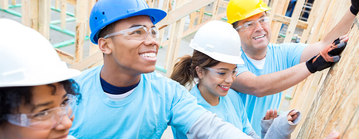 Group of people with hardhats framing house